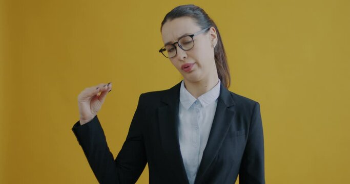 Portrait of young business lady making Bla bla bla hand gesture complaining of too much talk on yellow background. People and communication concept.