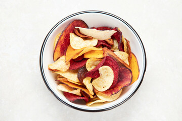 Vegetable organic chips made from potatoes, beets and carrots in a white plate for a snack, top view.
