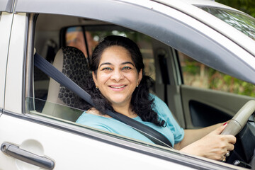 Happy indian mature woman driving a car in city. Safety and people concept.