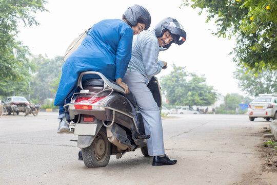 Mature Indian Couple Sitting On Motor Scooter With Flat Tire.