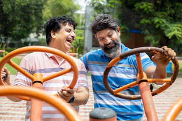 Obraz premium Indian mature senior men exercises on the public park gym equipment outdoor.