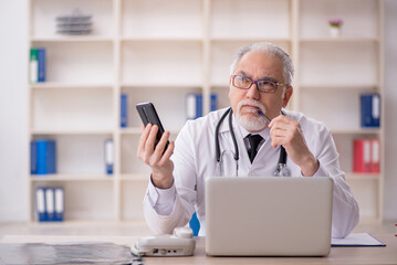 Old male doctor in telemedicine concept