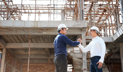 Fototapeta na wymiar Architect and construction worker engineers shaking hands while working at outdoor construction site.