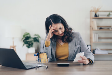 Young Asian Woman checking bills, bank account balance, taxes and calculating expenses at home
