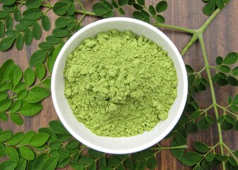 Moringa oleifera leaves powder in a bowl on wooden background 