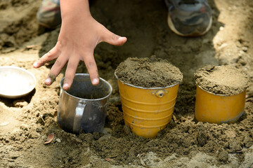 Children playing with sand in the sandbox in the schoolyard. Activity for fine motor skills, fill...
