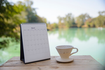 Desktop calendar, and cup of hot coffee placed on student wooden desk. calender for planner to plan daily appointments each day, month, and year on wooden table. Calendar background concept.