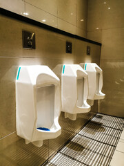 Selective focus image with noise effect white porcelain urinals in public toilet.