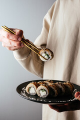 a man holds a plate of sushi.