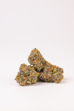 Group of dried cannabis nugs laying on a white surface