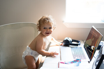 Cute baby boy with laptop computer on the table