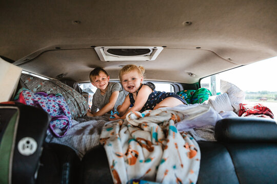 Kids in bed of truck camper ready for road trip