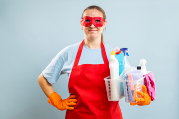 Woman in red mask, gloves and apron holding basket with cleaning supplies