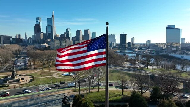USA flag with metropolitan Philly skyline. Phila downtown center city view. Aerial of Philadelphia Pennsylvania on sunny day.