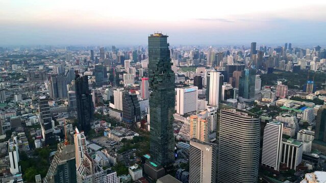 Drone Shot of Mahanakhon Tower skywalk, rooftop, in Bangkok, Silom area, business district, downtown. Circle around a skyscraper in Thailand.