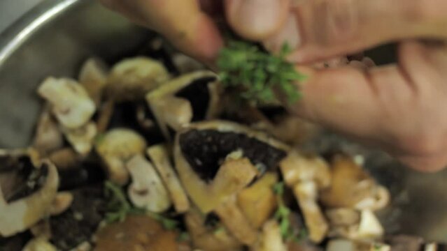 Adding fresh thyme to chopped mushrooms in pot ready to boil, close up