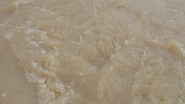 Tilt up shot of a flooded creek with muddy brown water and strong current - Kentucky