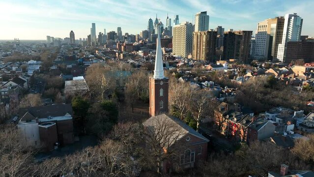 Christ Church and steeple with Philadelphia urban city skyline on sunny winter day. Aerial orbit.