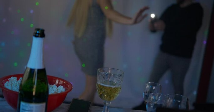 Beautiful blonde caucasian white girl women in front of led light wall in a dark night club scene dancing putting on show for phone camera with flash as her male man partner films for TikTok YouTube.