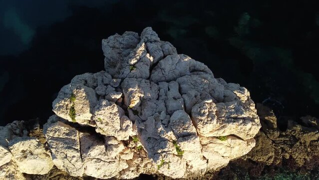 Breathtaking top down aerial view of offshore white rock formation surround by crystal clear turquoise water, orbit, rising day