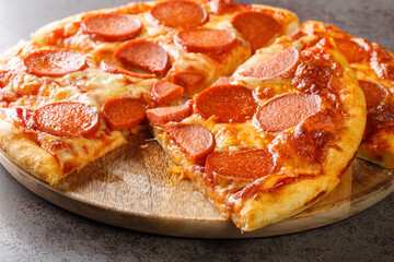 American pizza with pepperoni, mozzarella and tomato sauce close-up on a wooden board on the table. horizontal