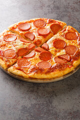 Hot homemade Pepperoni pizza ready to eat close-up on a wooden board on the table. Vertical
