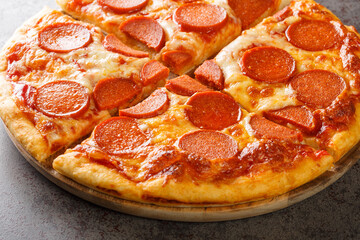 Freshly baked hot pepperoni pizza with sausages, mozzarella and tomato sauce close-up on a wooden board on the table. horizontal