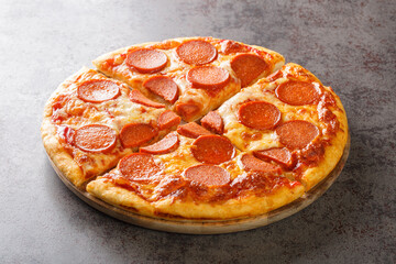 Hot homemade pepperoni pizza with cheese shavings closeup on the wooden board on the table. Horizontal
