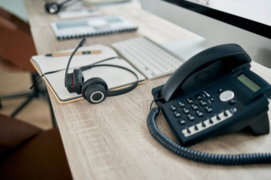 Telemarketing office, phone and VOIP on desk for communication, contact us and consulting by computer. Modern office, telephone and headphones on table for customer support, help or service with pc