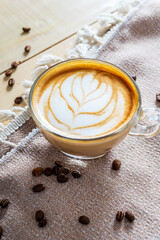 Cup of coffee latte with heart shape and coffee beans on fabric background
