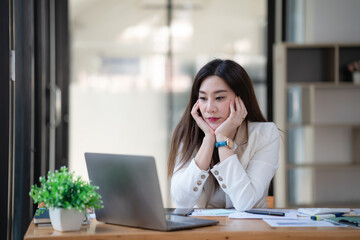 Asian businesswoman looking very bored at her desk.