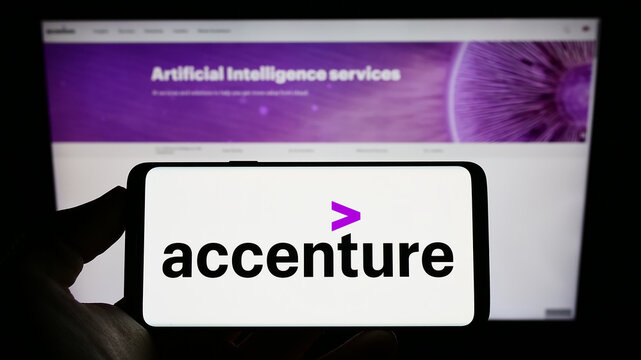 Stuttgart, Germany - 12-23-2022: Person holding mobile phone with logo of information technology company Accenture plc on screen in front of web page. Focus on phone display.