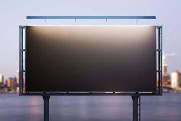 Obraz premium Blank black billboard on city buildings background at night, front view. Mockup, advertising concept
