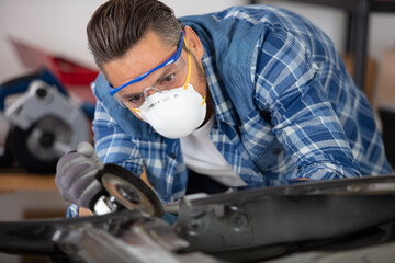 coachbuilder grinding a car part