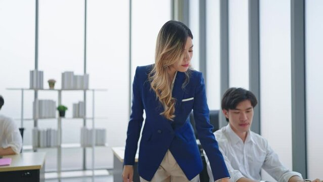 Asian woman manager walking and recheck the documents and talking to staff in the team at office