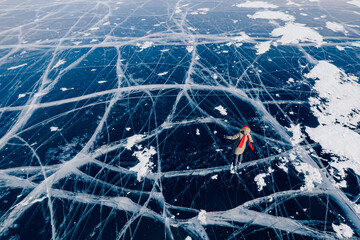 Woman tourist with red cap and scarf rides on skates on frozen ice of Lake Baikal