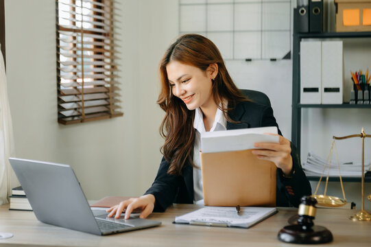 Attractive Young Lawyer In Office Business Woman And Lawyers Discussing Contract Papers Laptop And Tablet With Brass Scale On  Desk In Modern Office.