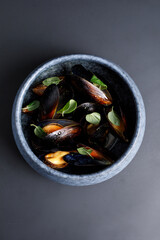 Bowl of grilled mussels over grey background