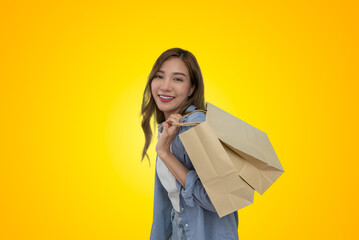 Obraz premium woman look at camera and holding shopping bag on yellow background.