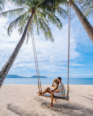 couple on the beach in Phuket relaxing on a beach swing chair, tropical beach in Phuket Thailand. Nakalay beach - obrazy, fototapety, plakaty
