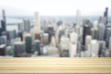 Empty wooden tabletop with beautiful blurry skyscrapers in the afternoon on background, mock up