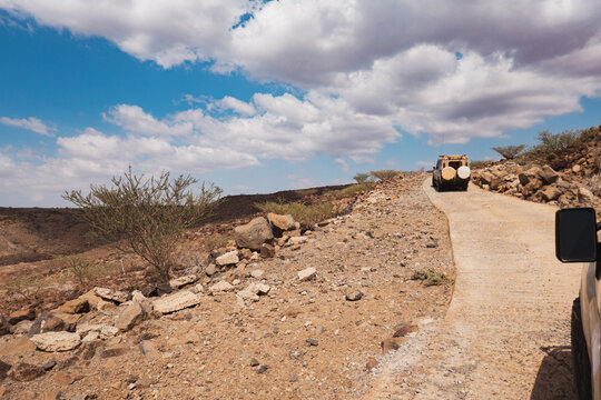 A tourist safari van on a dirt road in the desert at Lake Turkana, Loiyangalani, Kenya