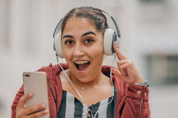 girl with headphones and mobile phone listening to music on the street excited