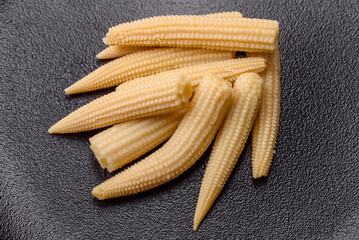 A bunch of small white canned corn on a dark concrete background