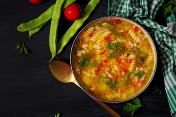 Minestrone, italian vegetable soup with pasta on black table. Top view, flat lay, copy space