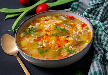 Minestrone, italian vegetable soup with pasta on black table.