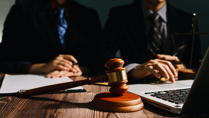 Business and lawyers discussing contract papers with brass scale on desk in office. Law, legal services, advice, justice and law concept picture with film grain effect