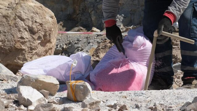 Pouring explosives into dug holes for quarry explosion. Explosive dust dumping into the excavated hole.