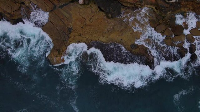 Above drone shot of rocks being lapped with waves . Ocean and sea stock videos