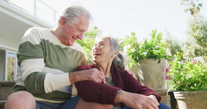 Happy Diverse Senior Couple Sitting On Stairs On Sunny Day In Garden